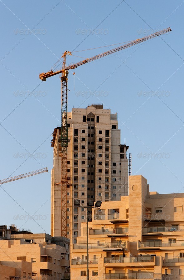 Lifting crane and building under construction at sunset