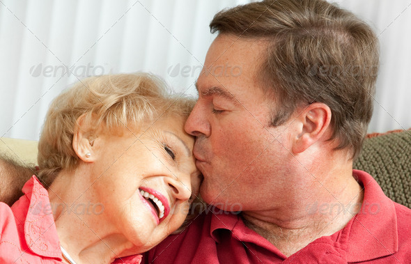 Adult man kissing his elderly mother on the forehead. Closeup portrait.