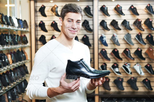 Young man at choosing shoe in clothes store