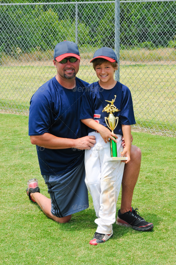 Father and son baseball portrait holding trophy.