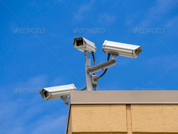 Three security cameras overlooking a mall parking lot