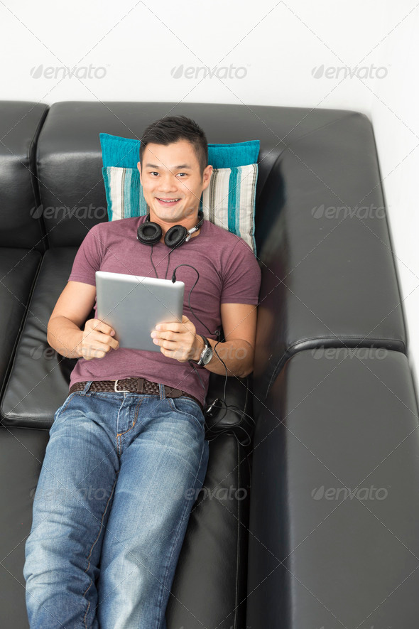 Chinese man sitting on sofa using Digital Tablet