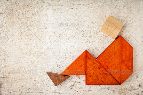 abstract sitting or relaxing figure built from seven tangram wooden pieces, a traditional Chinese puzzle game, rough white painted barn wood background