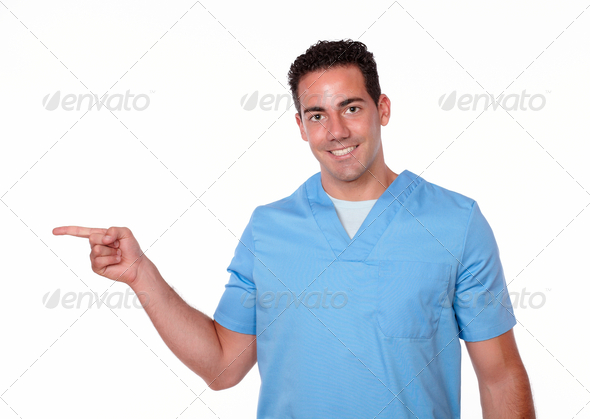 Portrait of a charismatic latin man on blue uniform pointing to his right while smiling at you on isolated background – copyspace