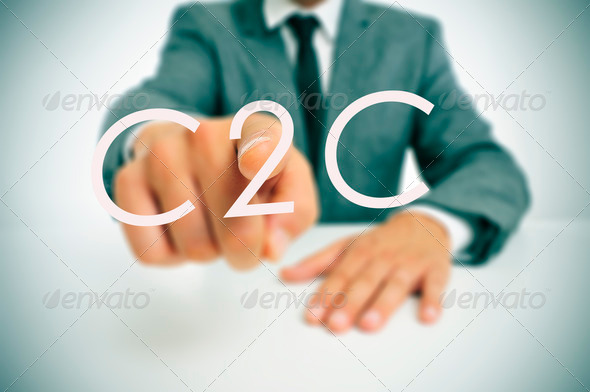 man wearing a suit sitting in a table pointing to the word C2C, consumer-to-consumer, written in the foreground