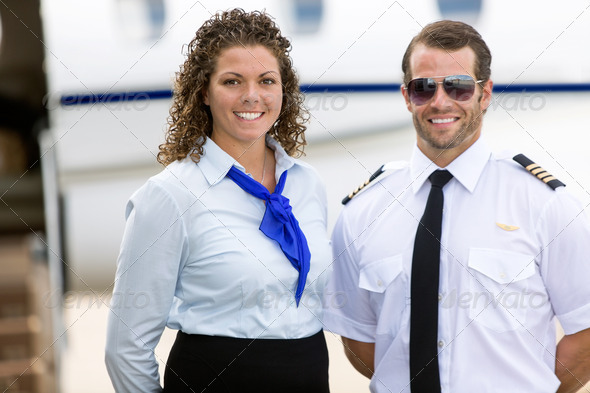 Stewardess And Pilot Standing Against Private Jet