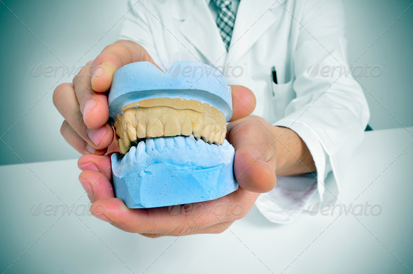 a dentist sitting in a desk showing a dental mould