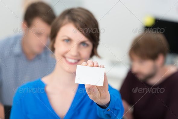Friendly businesswoman holding up a blank card for your credentials or contact details with focus to the card