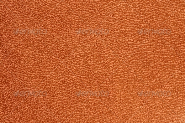 A macro shot of orange glossy patterned artificial leather background texture