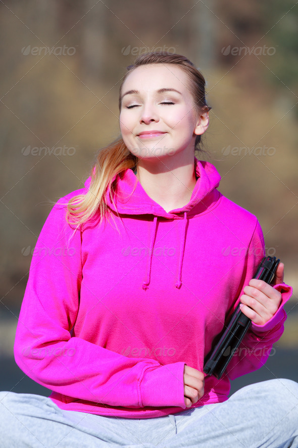 Woman teenage girl in pink with tablet getting some sun outdoor