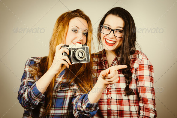 Funny hipster girls taking pictures with an old camera