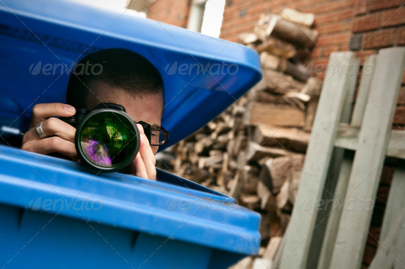 Paparazzi hiding in a blue garbage bin